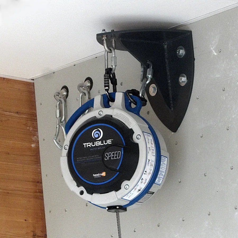 An auto-belay device bolted to the top of an indoor climbing wall